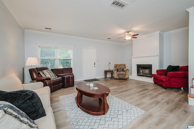 living area featuring visible vents, ornamental molding, a ceiling fan, and light wood-type flooring