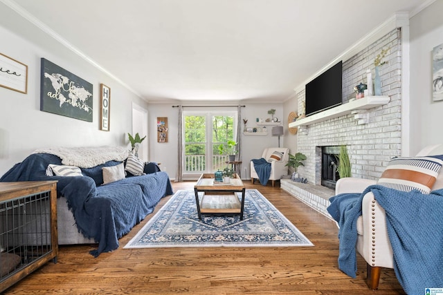 living area featuring a fireplace, wood finished floors, and crown molding
