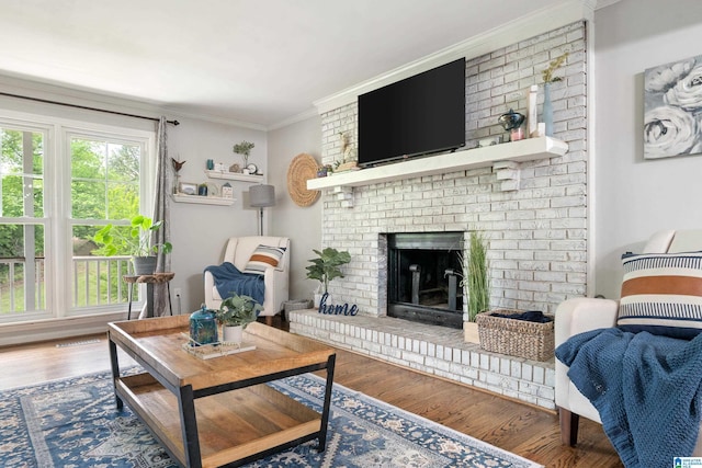 living room featuring wood finished floors, crown molding, and a brick fireplace