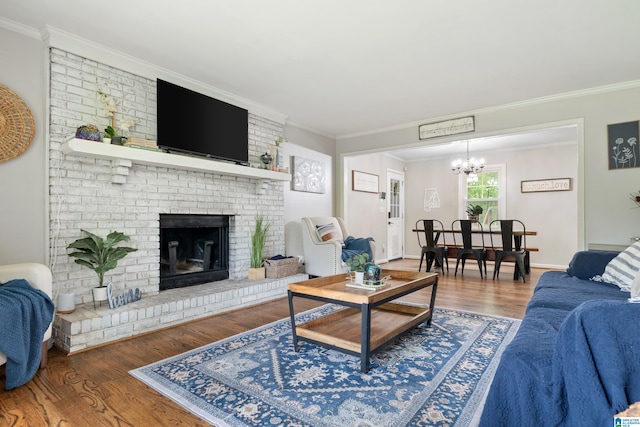 living room with crown molding, an inviting chandelier, a brick fireplace, and wood finished floors