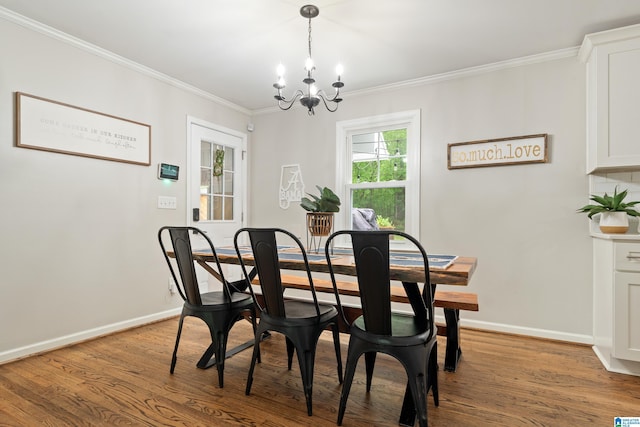 dining area featuring wood finished floors, a chandelier, crown molding, and baseboards