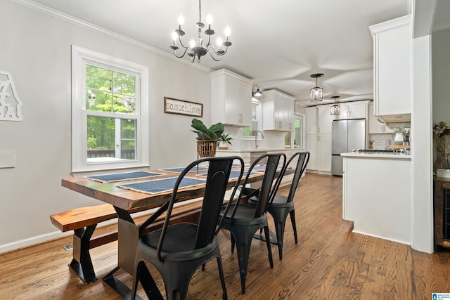 dining area featuring a chandelier, baseboards, ornamental molding, and light wood-style flooring
