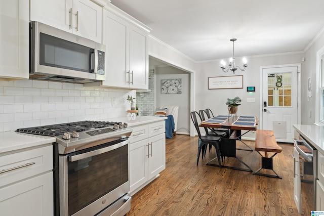 kitchen featuring ornamental molding, backsplash, appliances with stainless steel finishes, and light countertops
