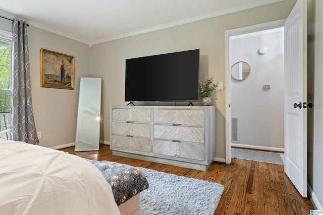 bedroom with ornamental molding, visible vents, wood finished floors, and baseboards