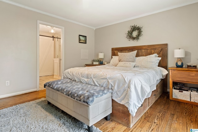 bedroom featuring wood finished floors, a barn door, ornamental molding, and baseboards