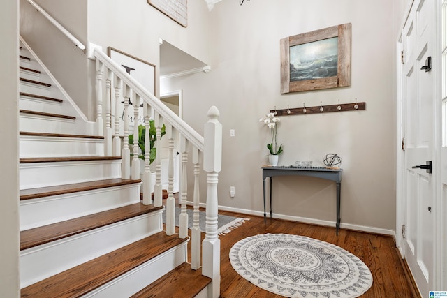 foyer featuring baseboards, wood finished floors, and stairs