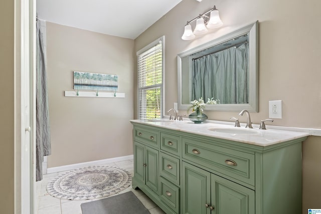 full bath featuring double vanity, tile patterned floors, baseboards, and a sink