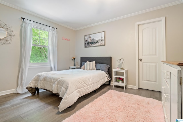 bedroom with baseboards, ornamental molding, and wood finished floors