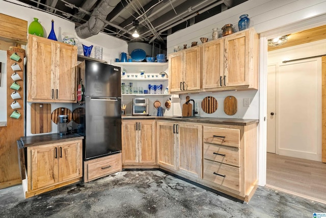 kitchen featuring a sink, light brown cabinets, open shelves, dark countertops, and freestanding refrigerator