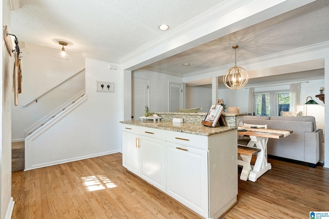 kitchen featuring white cabinetry, crown molding, a textured ceiling, and light wood finished floors