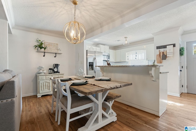 dining room featuring a chandelier, light wood-type flooring, ornamental molding, and a textured ceiling