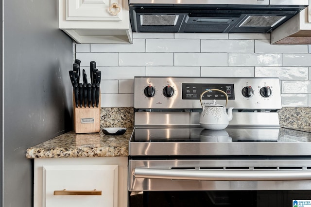 details featuring light stone countertops, stainless steel electric range oven, backsplash, range hood, and white cabinetry