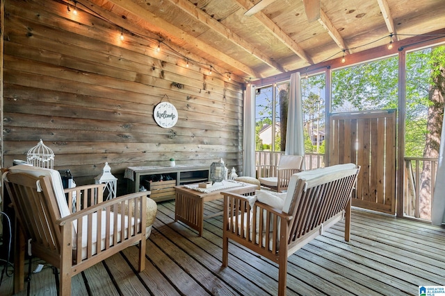 sunroom / solarium with a healthy amount of sunlight, an outdoor hangout area, and beamed ceiling