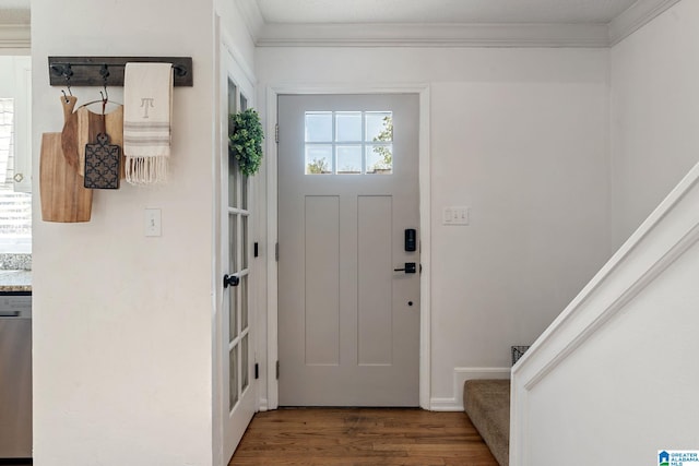 foyer entrance with ornamental molding, stairway, and wood finished floors