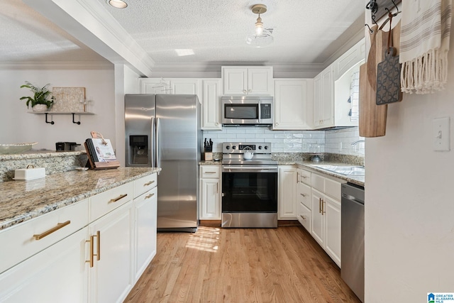kitchen featuring a textured ceiling, a sink, stainless steel appliances, light wood-type flooring, and ornamental molding