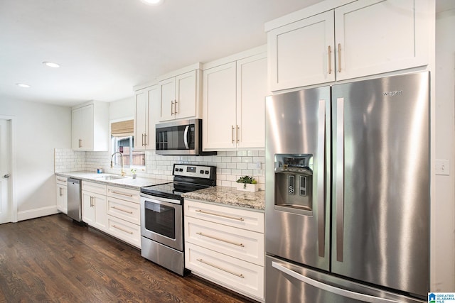 kitchen featuring a sink, appliances with stainless steel finishes, dark wood-style floors, light stone countertops, and backsplash