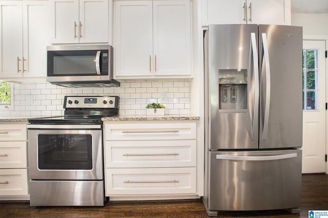 kitchen with light stone counters, appliances with stainless steel finishes, a wealth of natural light, and decorative backsplash