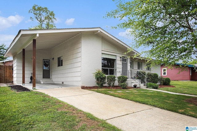 view of front of house with a front lawn, an attached carport, concrete driveway, and fence