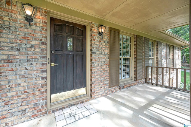 property entrance featuring a porch and brick siding