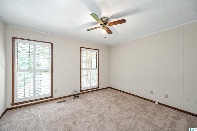 carpeted spare room featuring visible vents, crown molding, baseboards, and ceiling fan