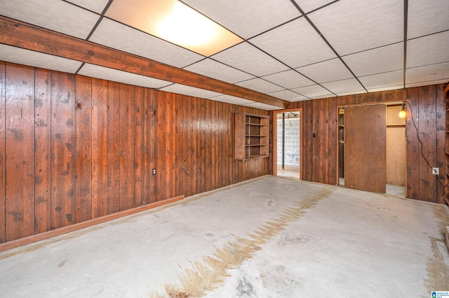 basement with wood walls and a drop ceiling