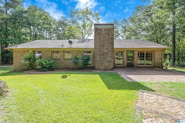 rear view of property featuring a lawn, a chimney, and brick siding