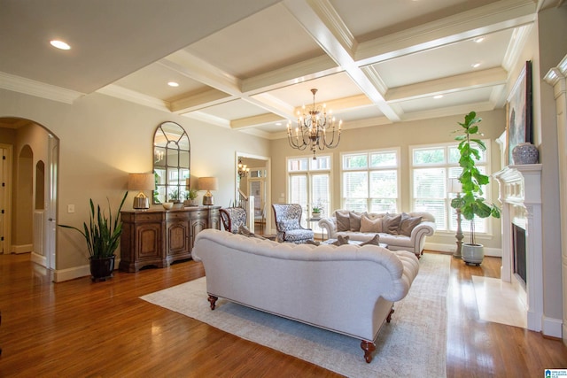 living area featuring arched walkways, a chandelier, beam ceiling, baseboards, and wood finished floors
