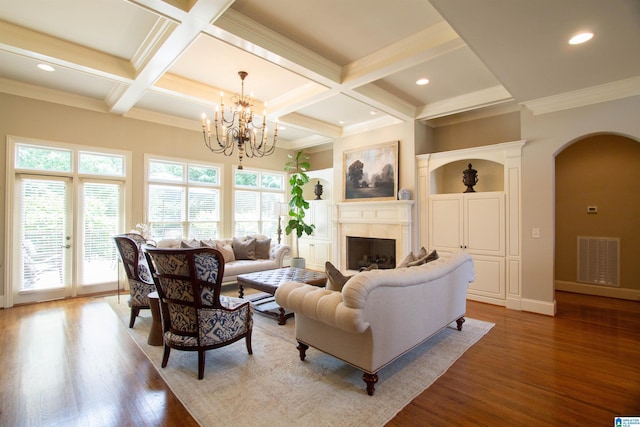 living area featuring arched walkways, wood finished floors, beamed ceiling, coffered ceiling, and a fireplace