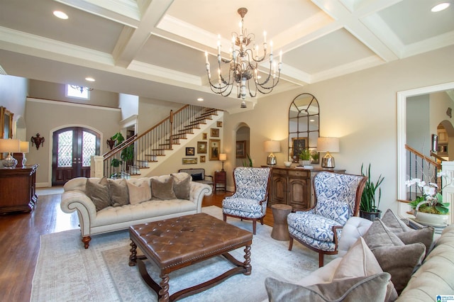 living room with arched walkways, stairway, coffered ceiling, wood finished floors, and a chandelier
