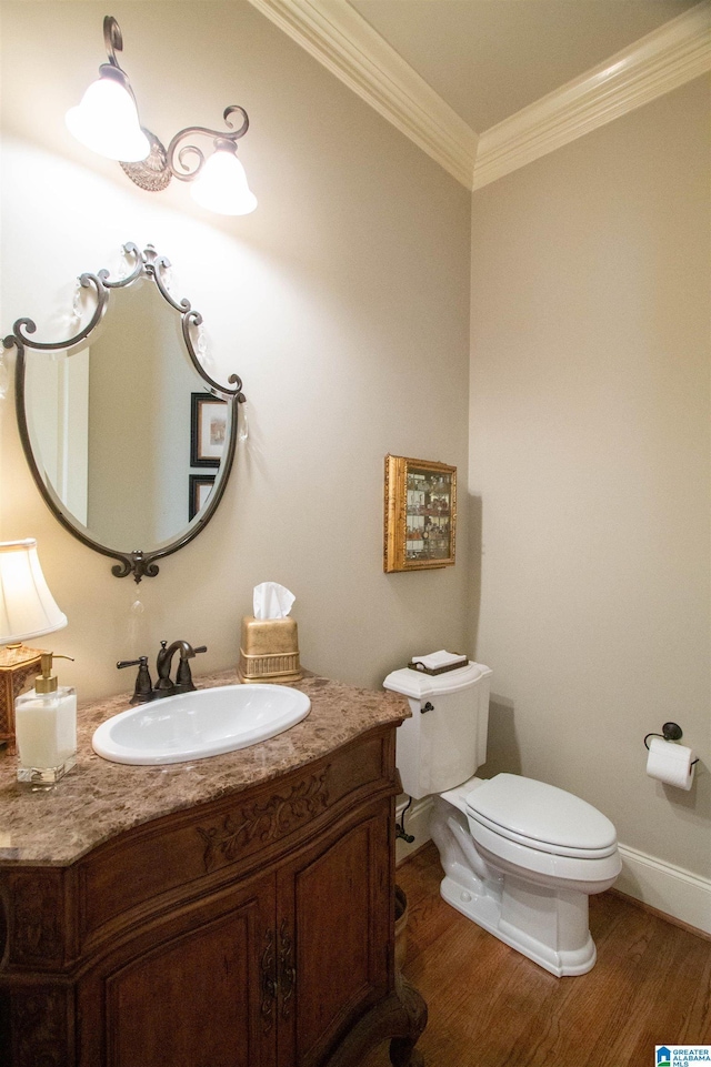 bathroom with ornamental molding, toilet, wood finished floors, vanity, and baseboards