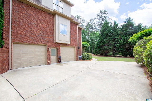 view of side of home featuring concrete driveway, a garage, and brick siding