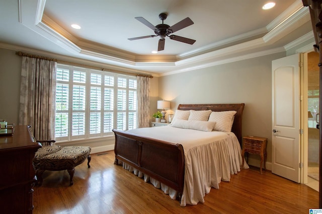 bedroom featuring a tray ceiling, wood finished floors, ornamental molding, a ceiling fan, and recessed lighting