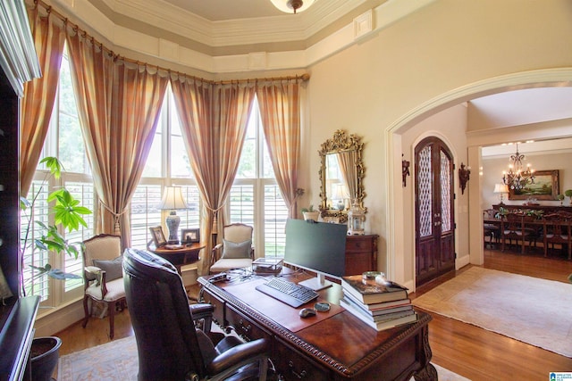 office space featuring a chandelier, arched walkways, ornamental molding, and wood finished floors