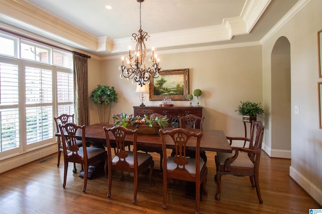 dining area featuring arched walkways, a tray ceiling, healthy amount of natural light, a chandelier, and ornamental molding