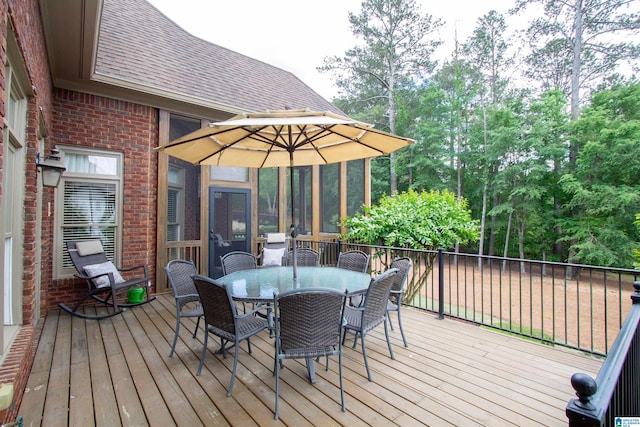 deck with outdoor dining area and view of scattered trees