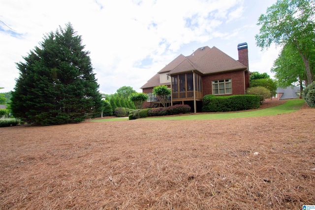 view of front of home with a sunroom, a chimney, and brick siding