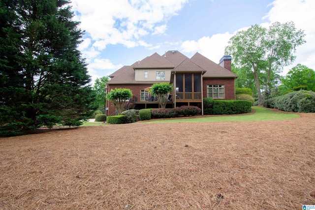 view of front of property with a sunroom, a chimney, and a front lawn