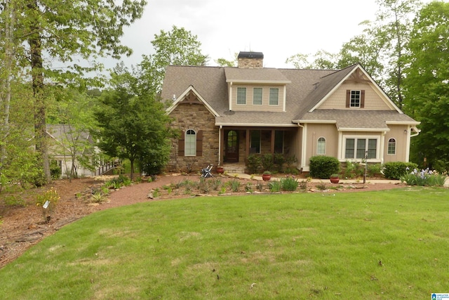 craftsman-style house featuring roof with shingles, a front lawn, stone siding, a porch, and a chimney
