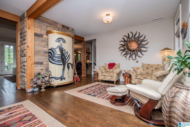 living area with visible vents, wood finished floors, and beam ceiling