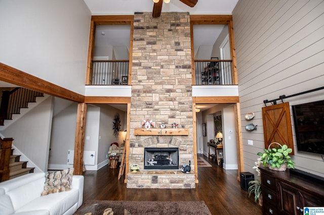 living room featuring stairs, a high ceiling, a stone fireplace, and ceiling fan