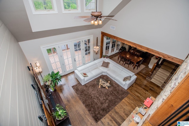 living room featuring a high ceiling, visible vents, french doors, and wood finished floors