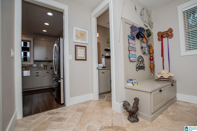 hallway featuring baseboards, recessed lighting, and stone tile flooring