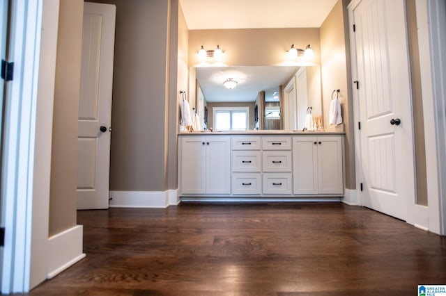 bathroom featuring double vanity, baseboards, and wood finished floors
