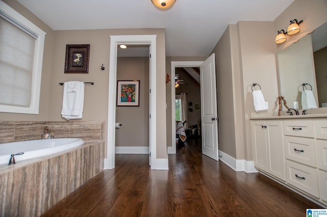 full bath featuring baseboards, wood finished floors, a garden tub, and vanity