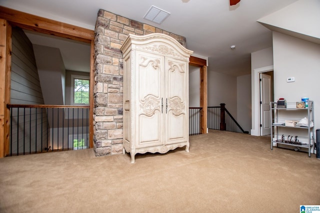 interior space featuring carpet flooring, ceiling fan, an upstairs landing, and visible vents