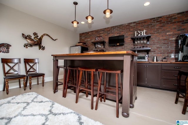 bar featuring brick wall, recessed lighting, finished concrete floors, wet bar, and hanging light fixtures