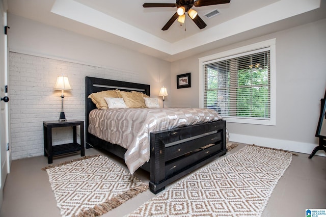 bedroom featuring a ceiling fan, a tray ceiling, visible vents, and baseboards