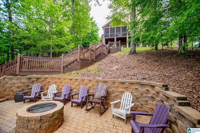 view of patio / terrace featuring stairway, a sunroom, and an outdoor fire pit