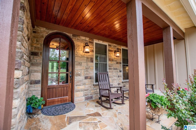 view of exterior entry with a porch, board and batten siding, and stone siding