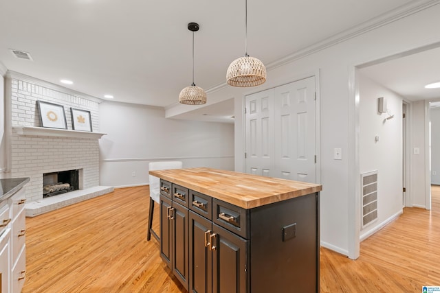 kitchen featuring light wood finished floors, wooden counters, visible vents, baseboards, and hanging light fixtures